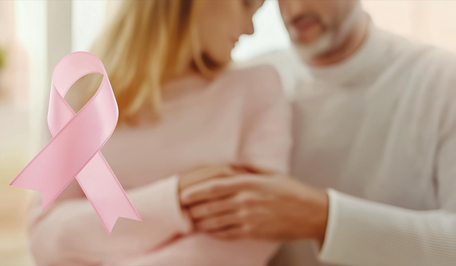 Pareja abrazada junto a un listón rosa de concientización sobre el cáncer