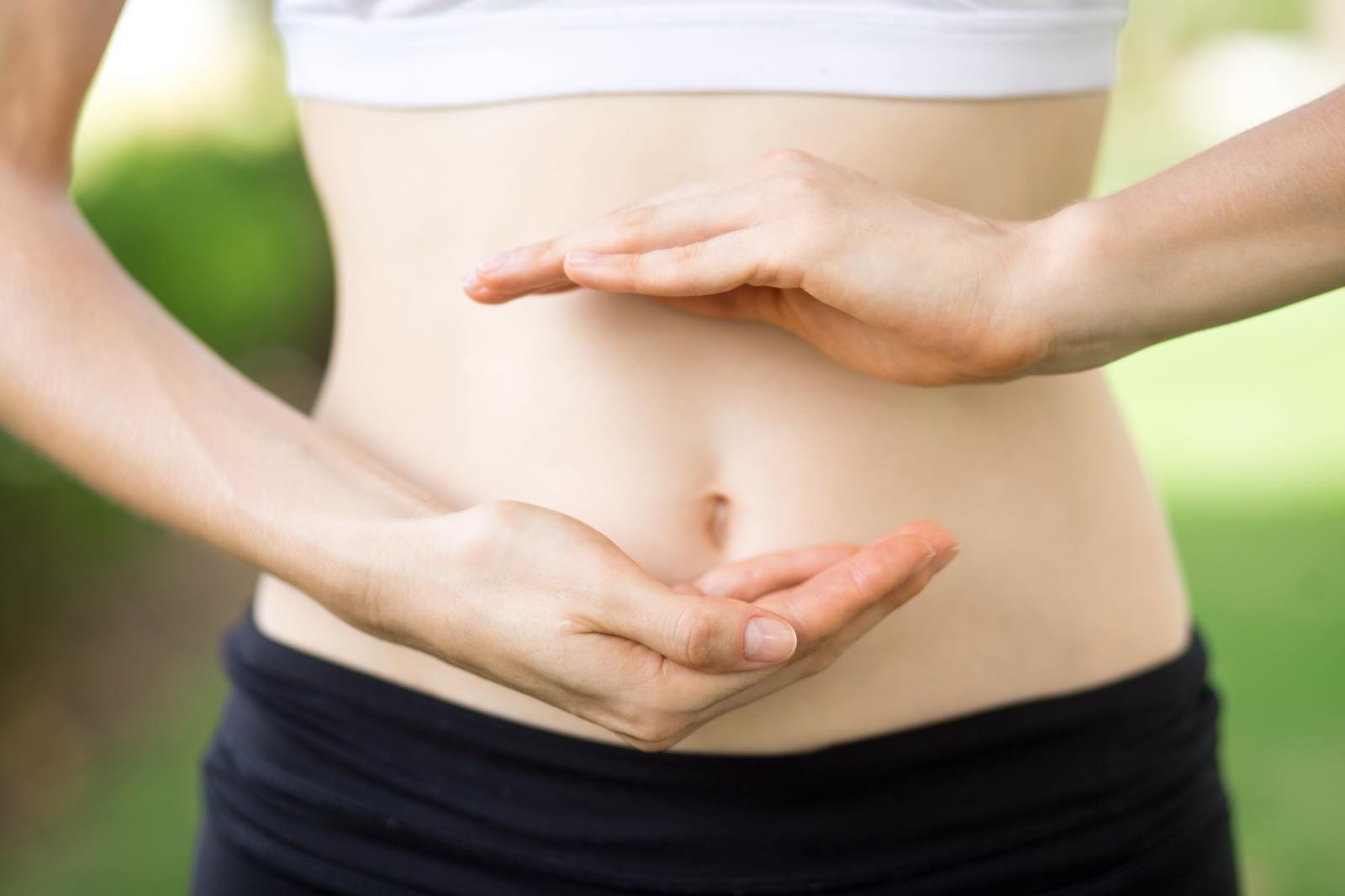 Manos formando un círculo alrededor del abdomen, en alusión a la salud intestinal