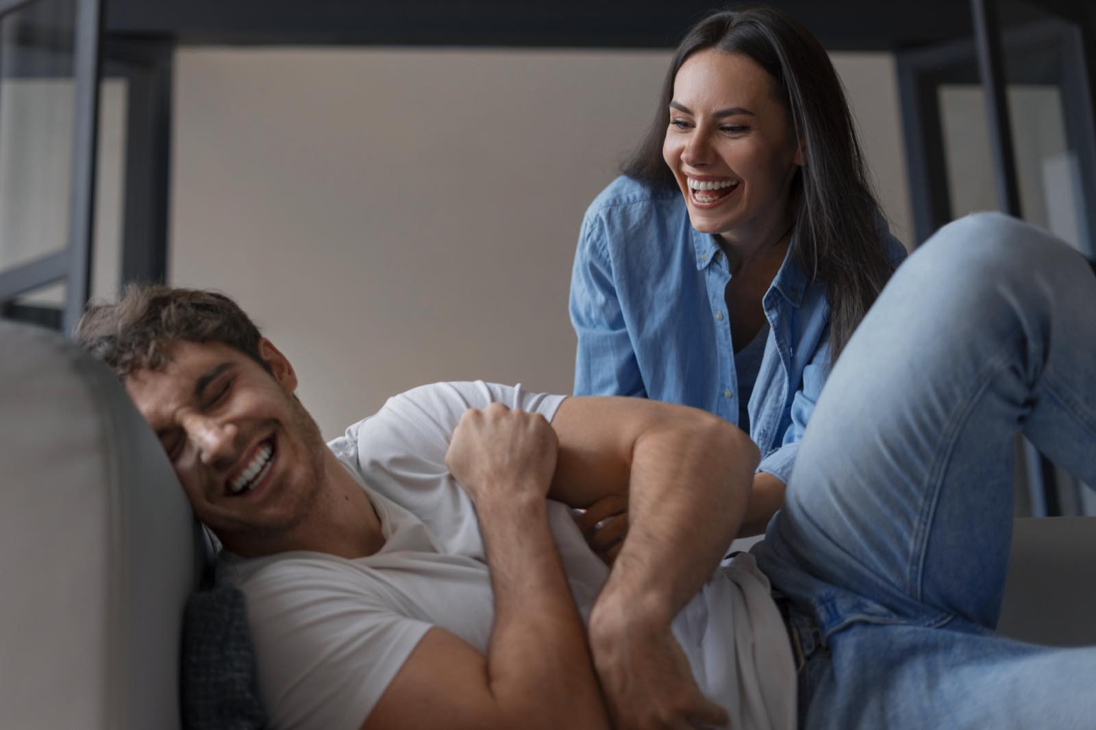 Pareja riendo en un sillón, en un momento de complicidad y cercanía