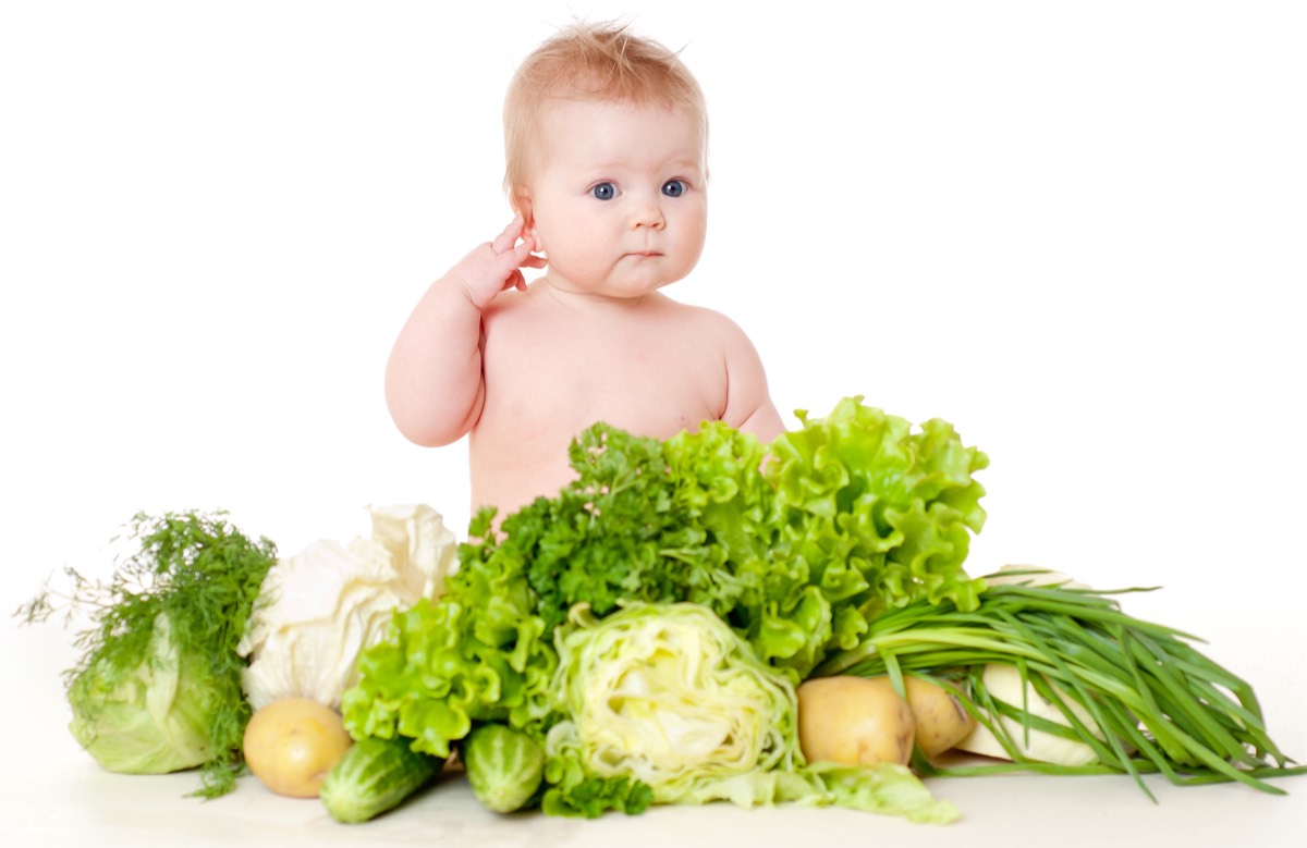 Bebé rodeado de verduras frescas, símbolo de la intervención nutricional de la Medicina Metabólica de Ingenes